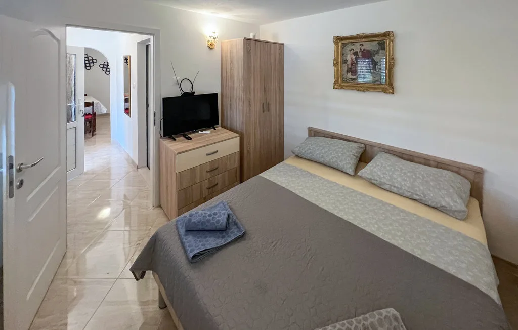 A bedroom with a double bed, a wardrobe, and a television on a dresser.