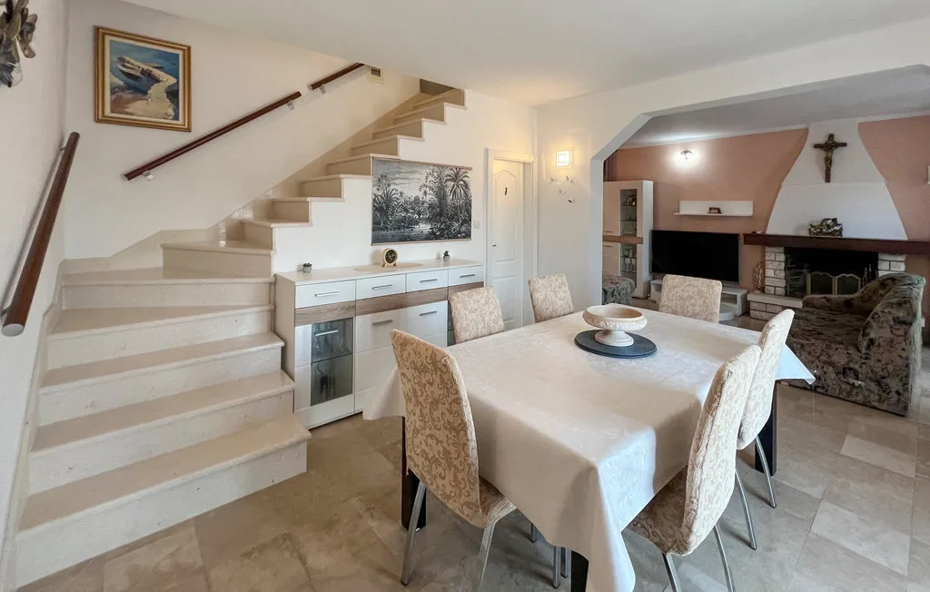 A dining area with a table beside a staircase and living room.