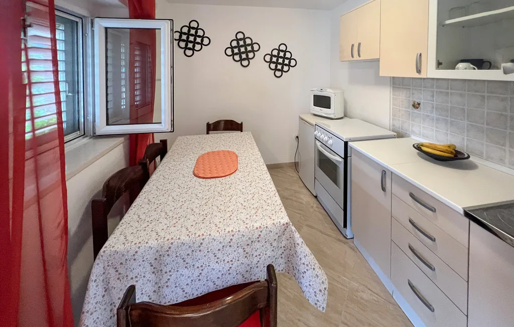 A kitchen and dining area with a long table beside the cooking counters.
