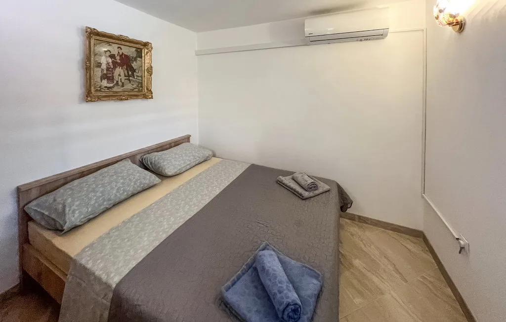 A bedroom with a made bed and an air conditioner mounted on the wall.