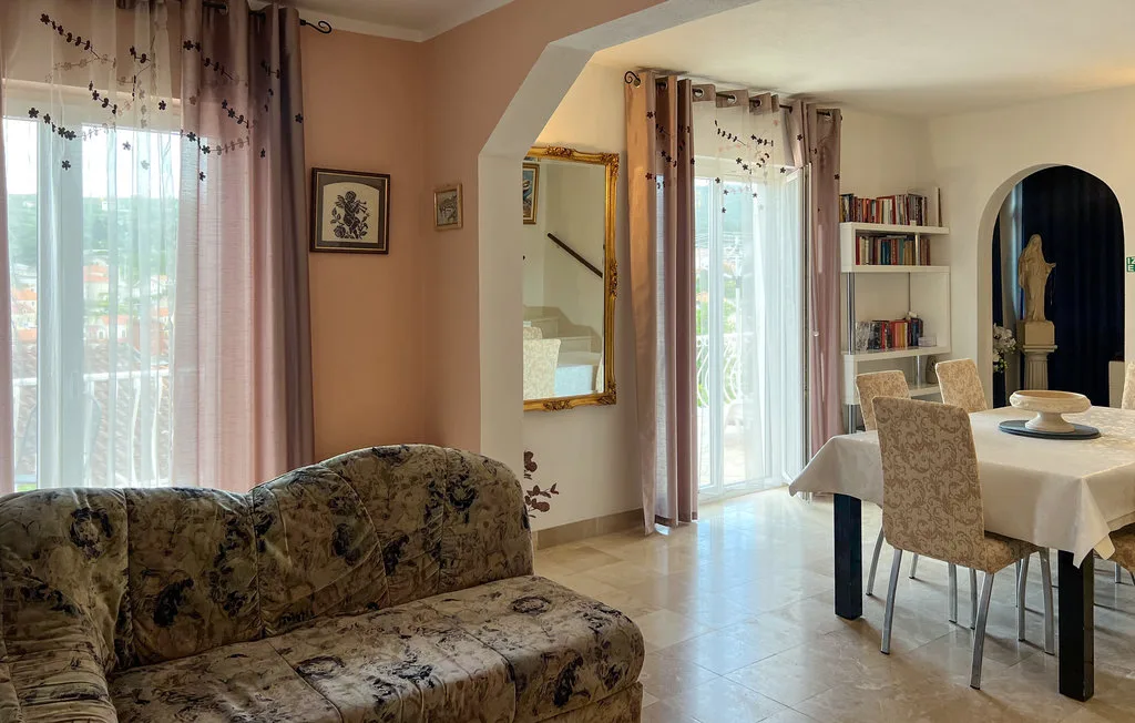 A living and dining area with a patterned sofa and a table by the windows.