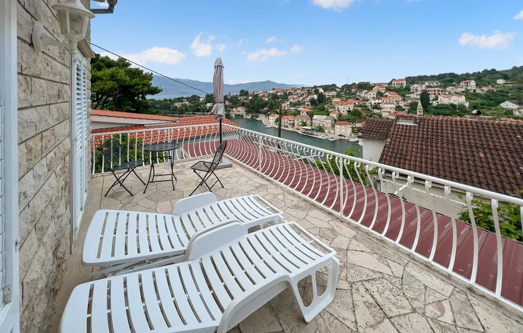 A stone-paved terrace with lounge seating overlooks a hillside town.