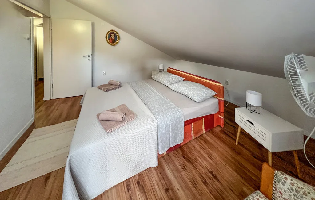 A bedroom with a red bed, white bedding, and a sloped ceiling.