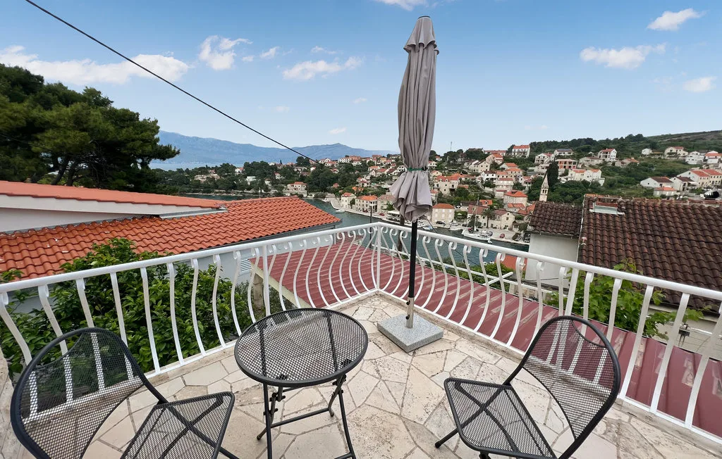 A tiled terrace with metal seating overlooks a hillside town.