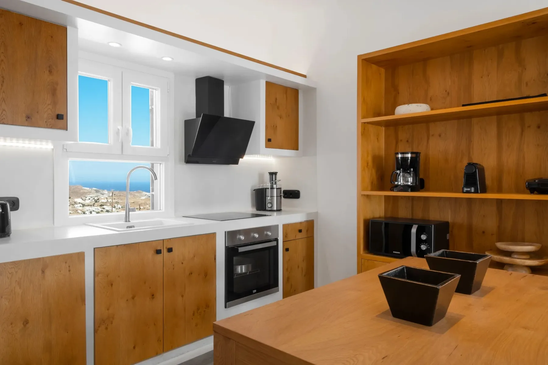 A bright kitchen with wooden cabinets, a countertop, and a view through the window.