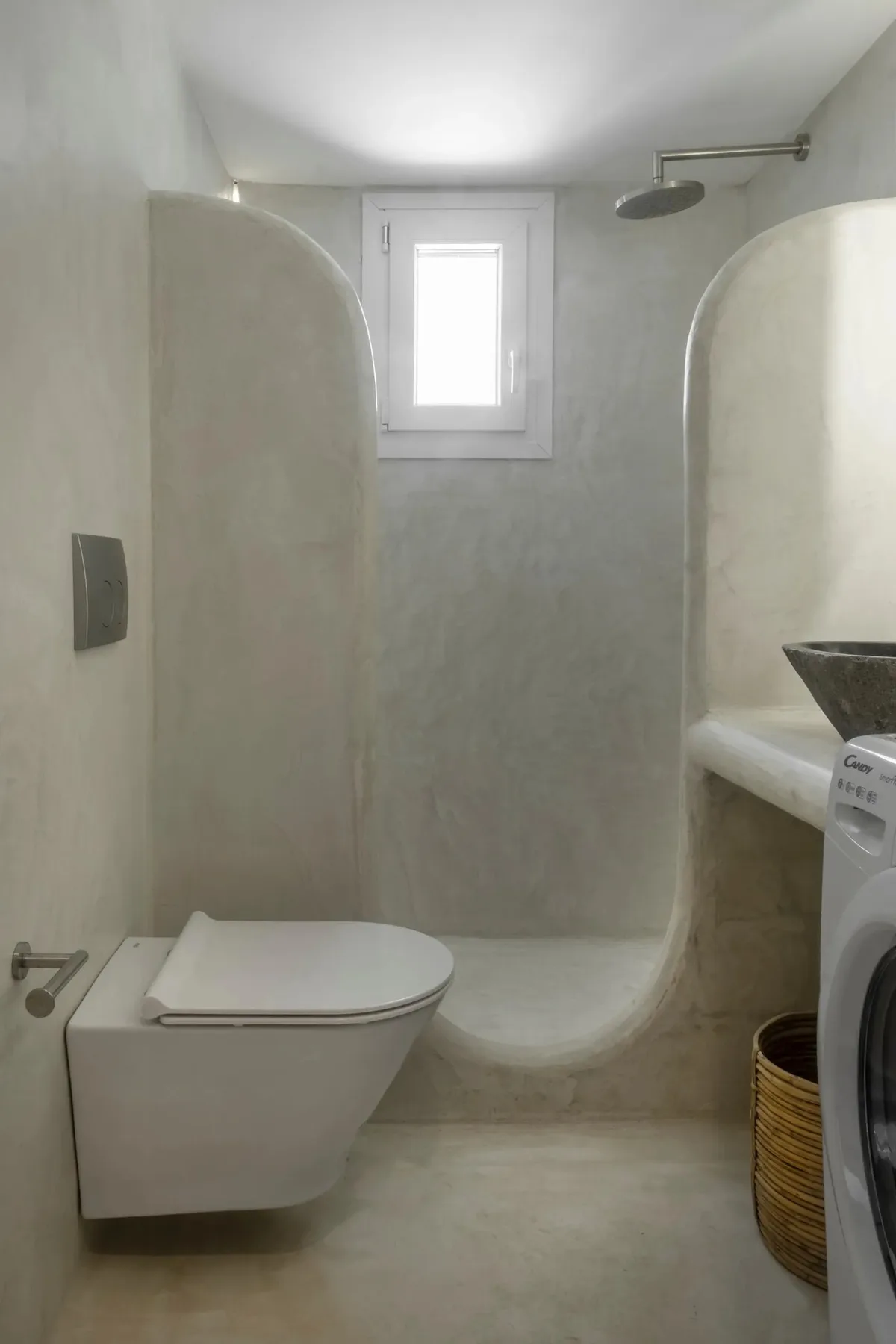 A bathroom with a toilet, shower, and washing machine.
