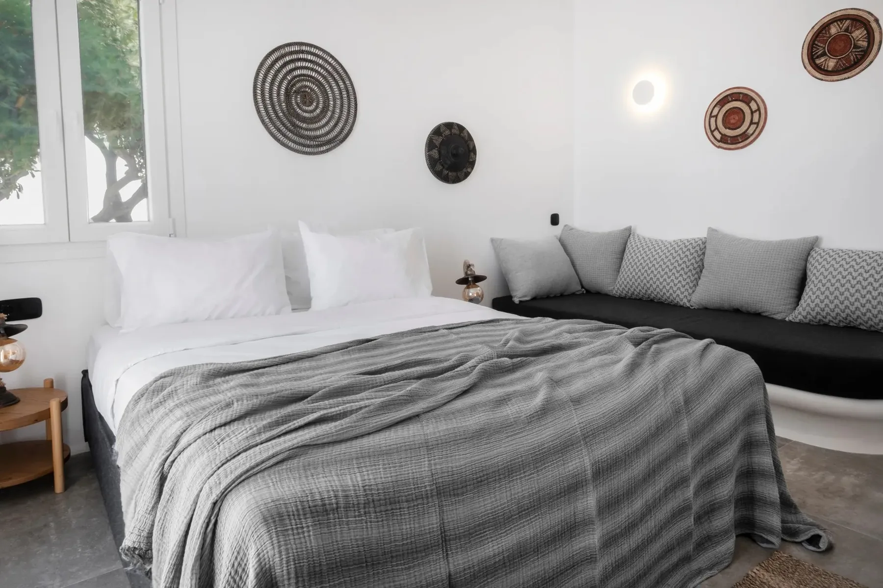 A bedroom with a bed and a dark seating area along the wall.