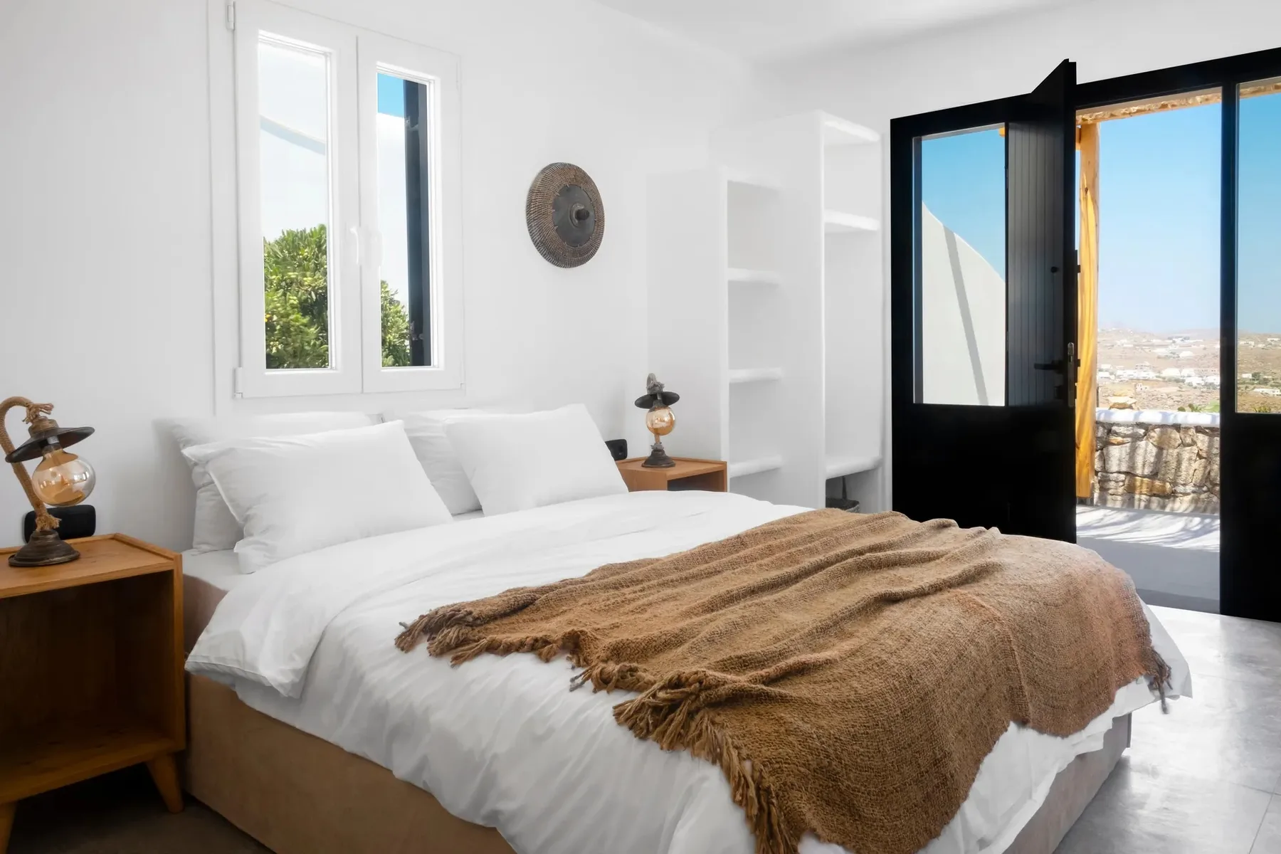 A bright bedroom with white bedding and an open balcony door.