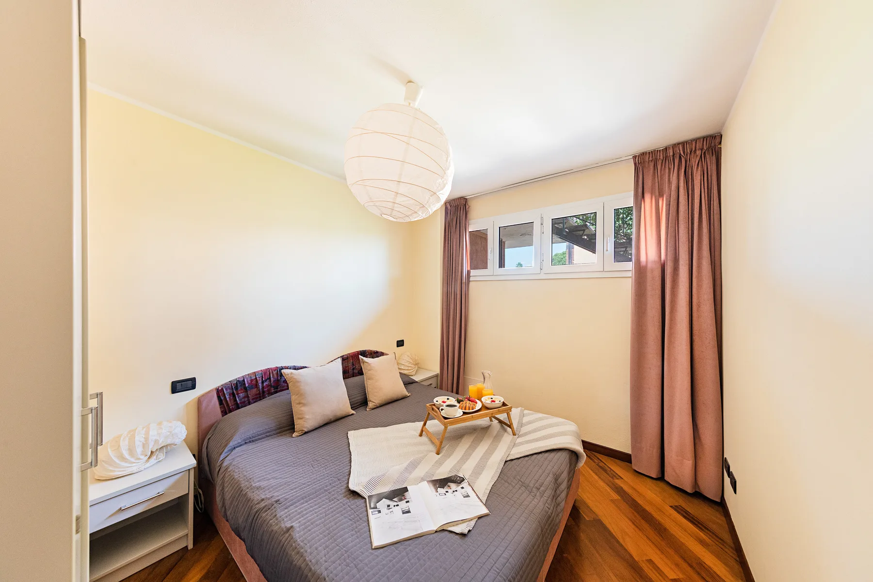 A bedroom with a bed, a small bedside table, and a curtained window.