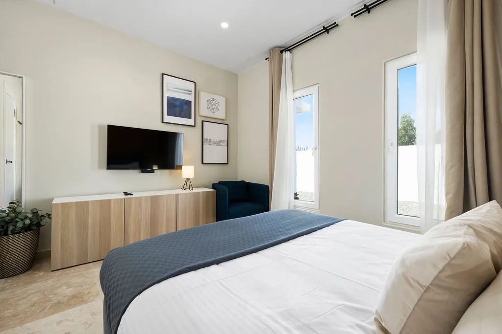 Step into your serene bedroom retreat, where crisp linens invite restful sleep and bright windows frame tranquil views. Relax in modern comfort with a stylish TV, cozy seating, and a peaceful ambiance designed just for you.