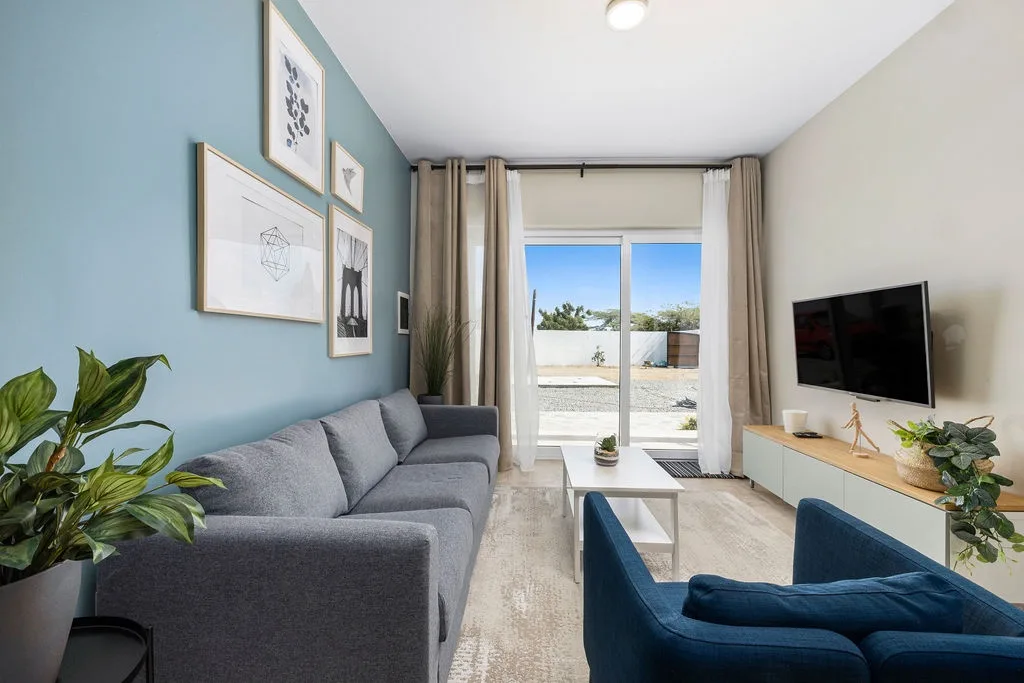 Unwind in this bright and modern living room, where sunlight pours through sliding glass doors and comfortable seating invites you to relax and recharge in style.