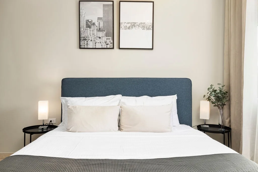 Sink into crisp white linens and plush pillows after a day of exploring. Your bedroom awaits with calming tones, modern art, and soft bedside lighting for total relaxation.