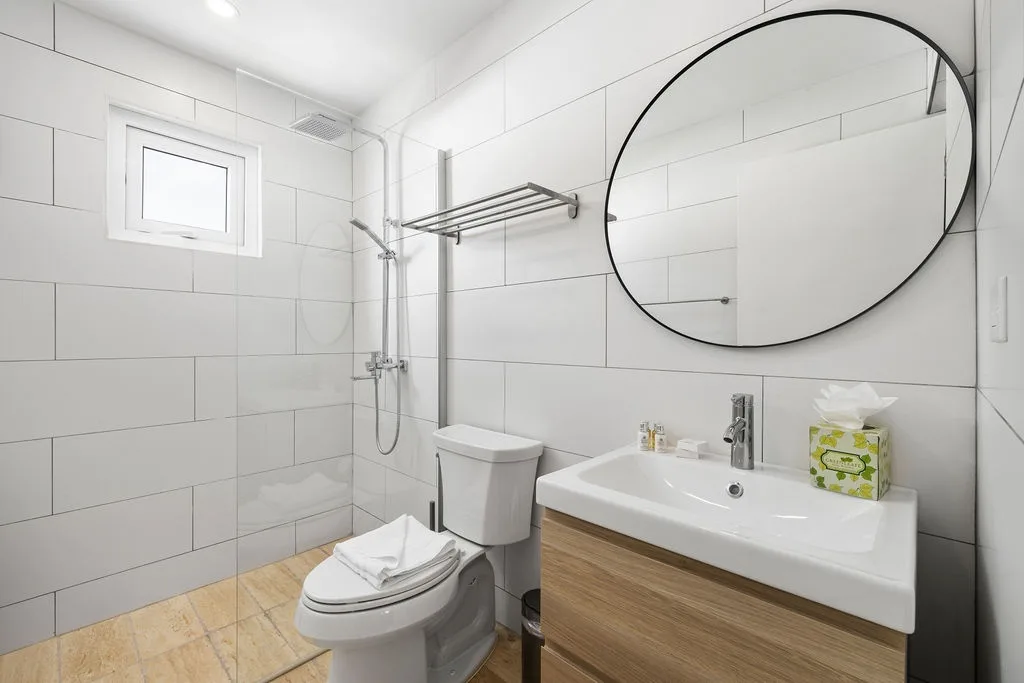 Refresh in your modern bathroom with crisp white tiles, a rainfall shower, and warm wood accents that create a spa-like sanctuary after a day exploring.