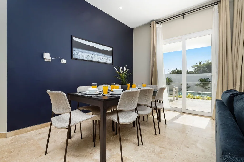 Gather for meals around your stylish dining table, with bold navy accents and doors opening to your private terrace overlooking lush greenery and sea views.