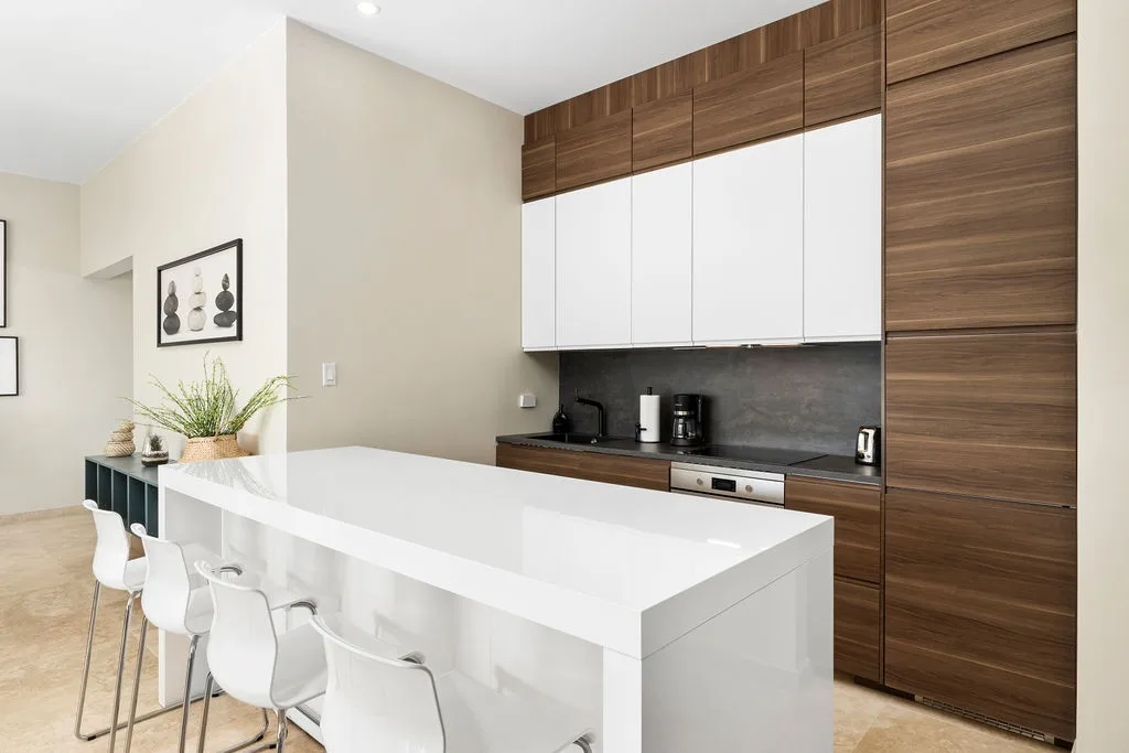 Modern elegance meets comfort in your fully equipped kitchen, featuring sleek wood cabinetry, a spacious island with bar seating, and everything you need to prepare your favorite meals.
