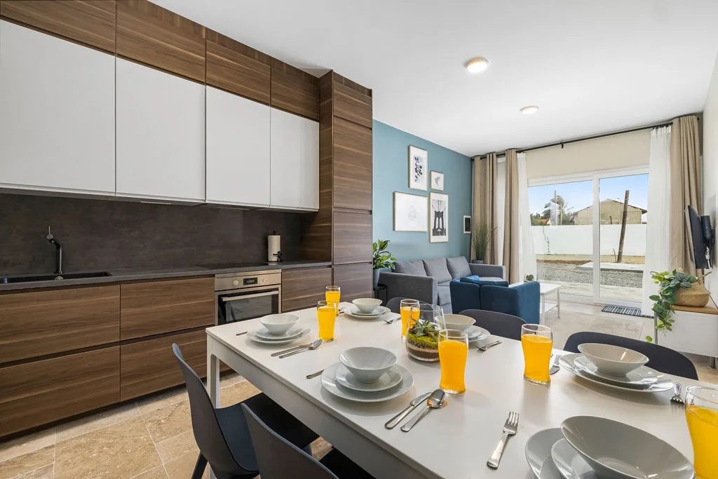 Your open-concept space blends modern kitchen, dining, and living areas with sleek wood finishes, pops of color, and natural light streaming through sliding doors to your private terrace.