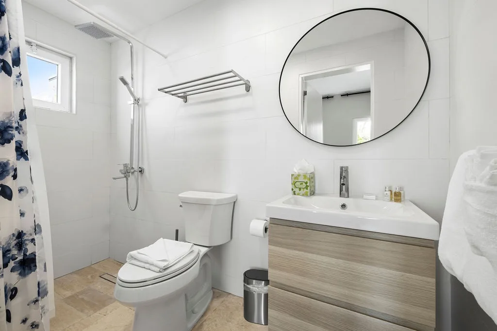 Step into your private bathroom, where crisp white tiles and modern fixtures create a serene retreat. Fresh towels await, and natural light streams through the window.