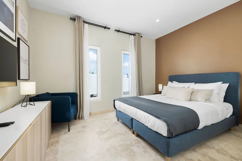 Settle into your restful bedroom with its plush king bed, soft linens, and warm natural light streaming through tall windows—your peaceful retreat after a day of exploring.