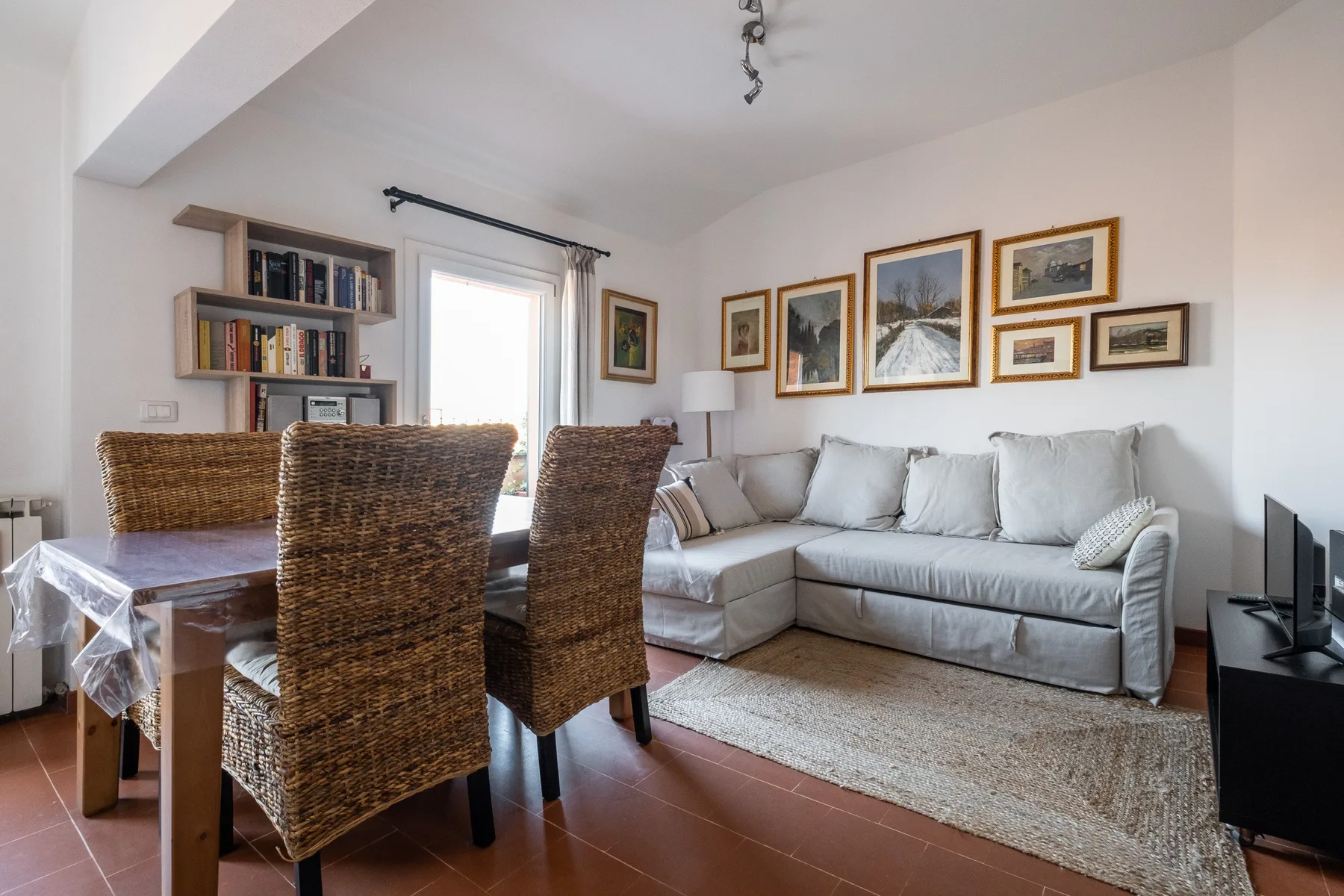 A living and dining area with a light-colored sectional sofa and a dining table.
