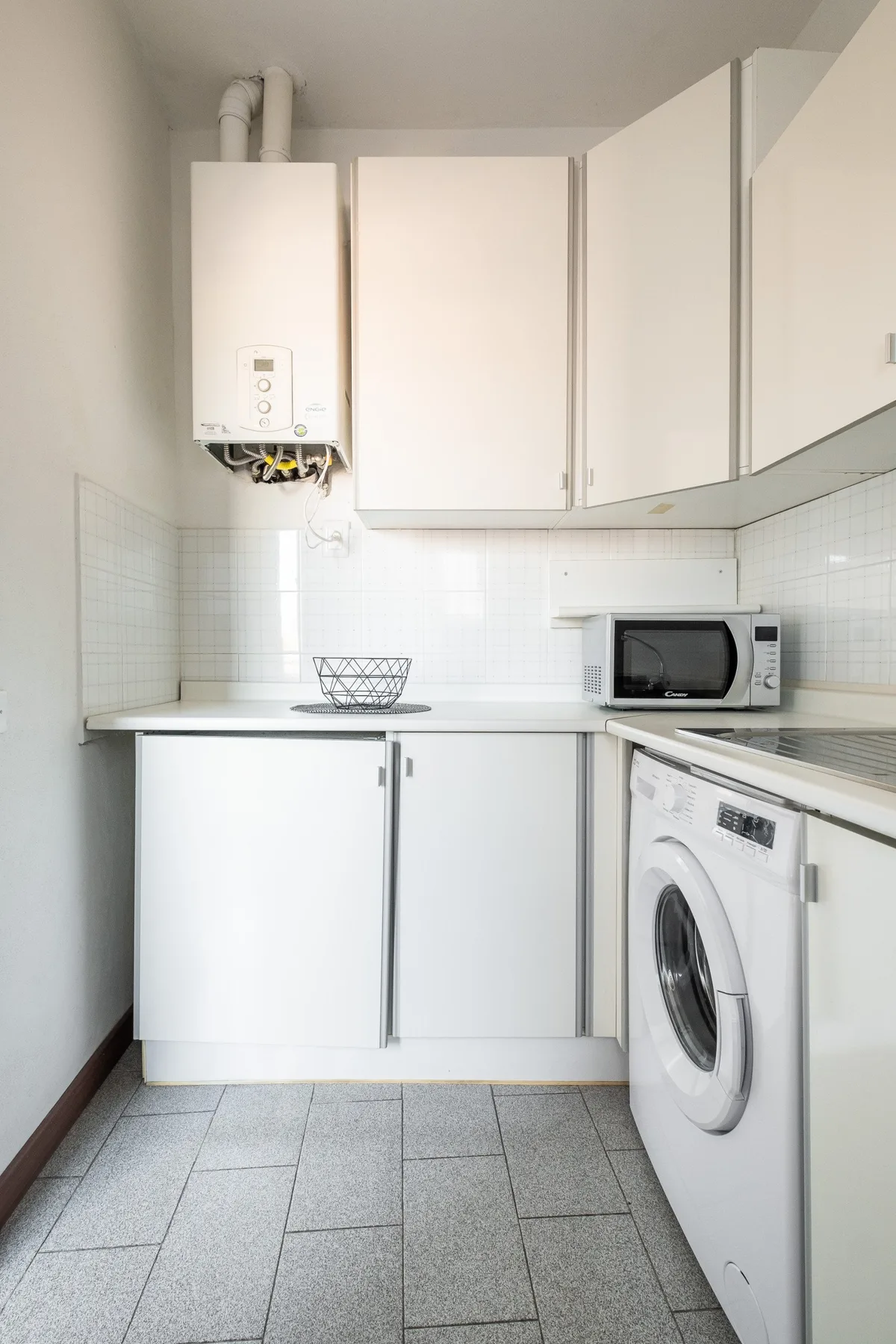A compact kitchen with white cabinets, a countertop, and a washing machine.