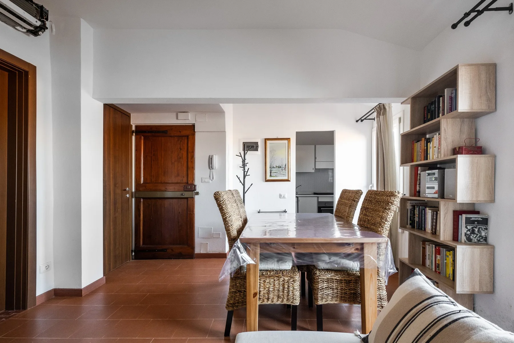 A dining area with a wooden table and chairs beside a wall of bookshelves.