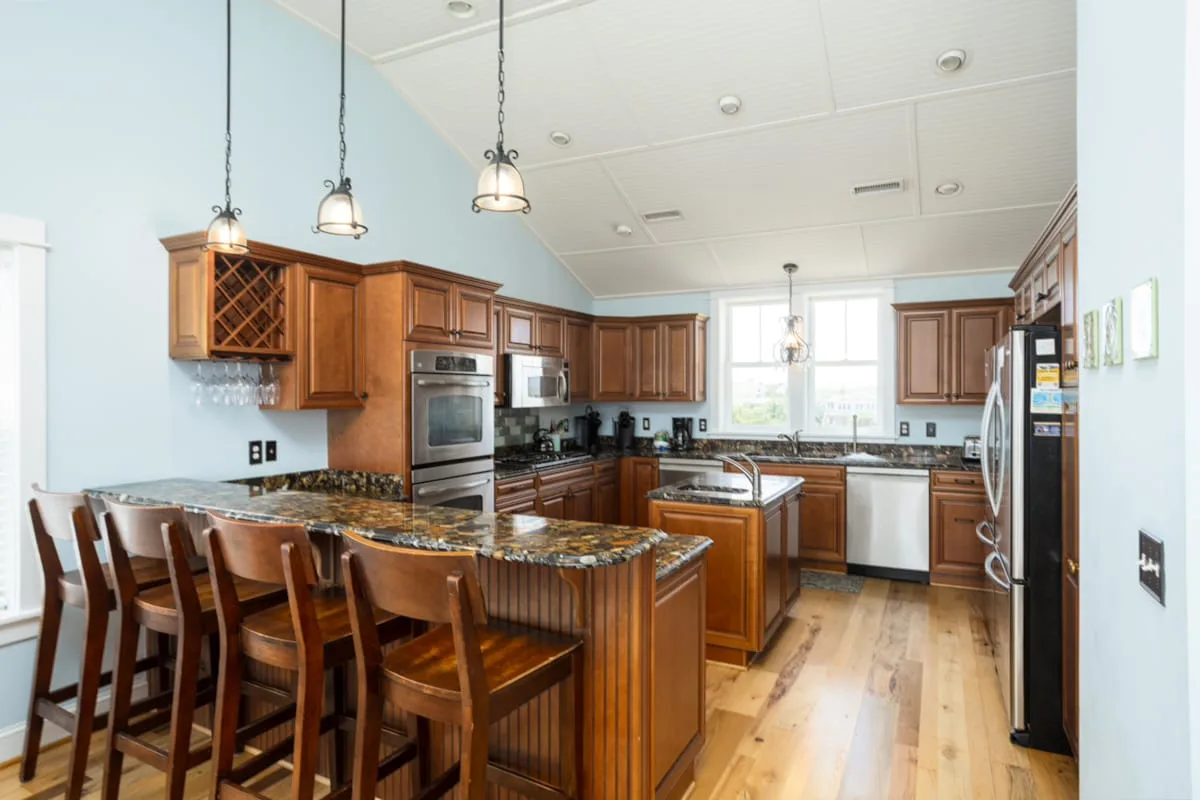 Una cocina amplia con gabinetes de madera, una isla central y una barra para comer.