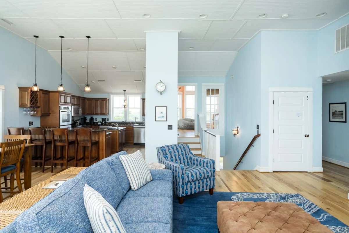 Sala de estar y cocina de concepto abierto, con asientos azules y comedor.