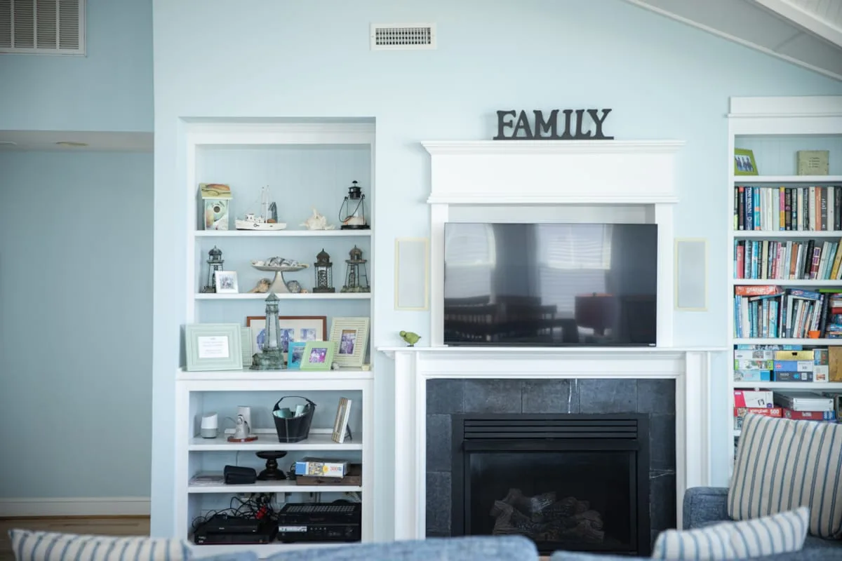 Una sala de estar con un televisor sobre una chimenea y estanterías empotradas.