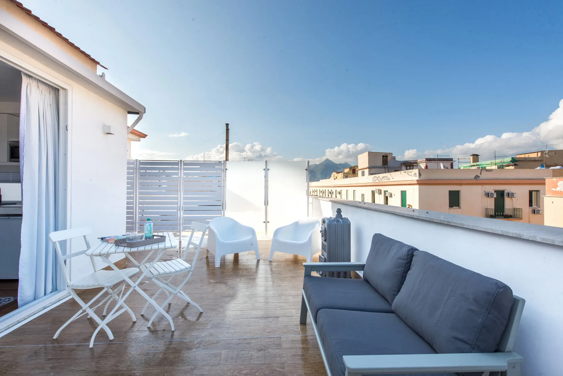 A rooftop terrace has outdoor seating and views of nearby buildings.