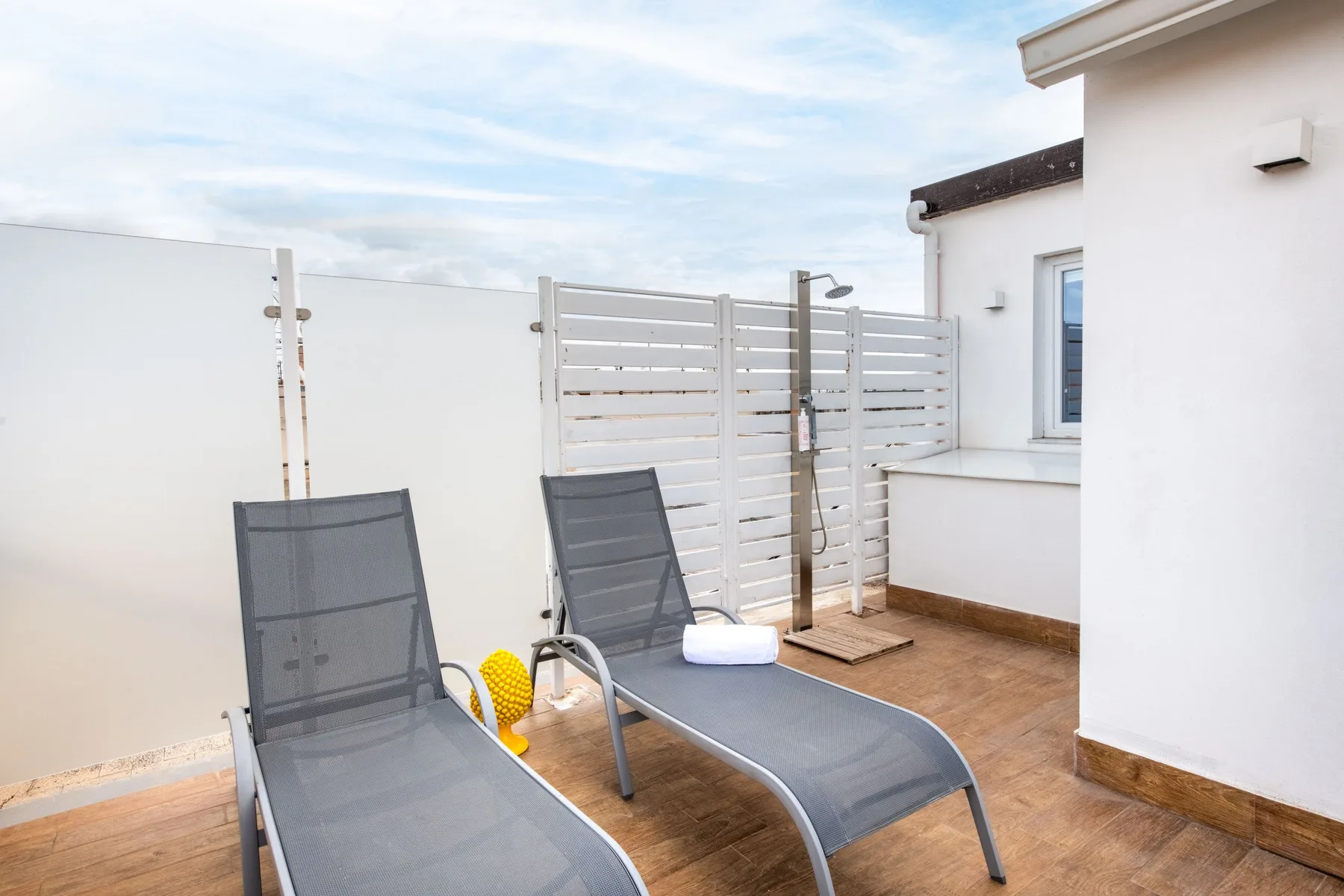 A small outdoor terrace with reclining seating and a slatted privacy screen.