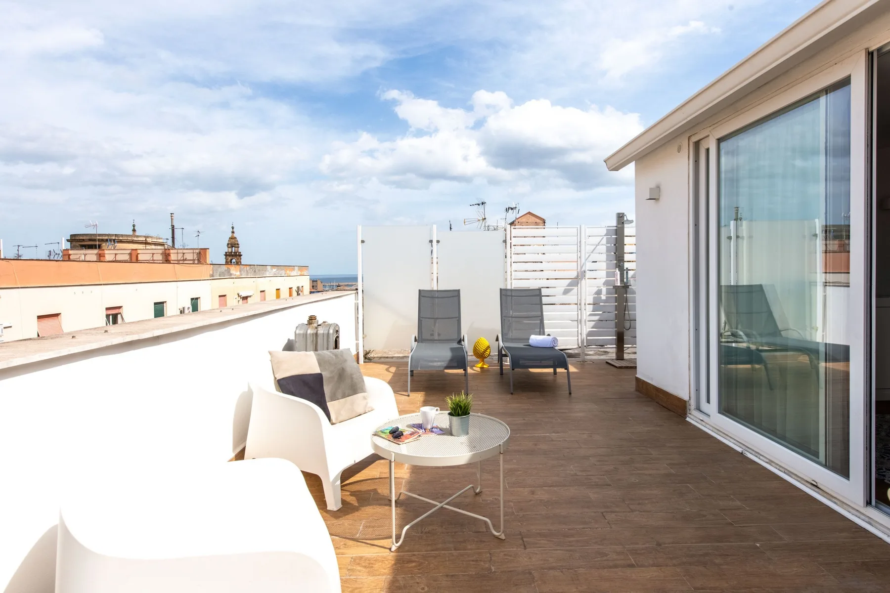 A rooftop terrace with outdoor seating and a glass door.