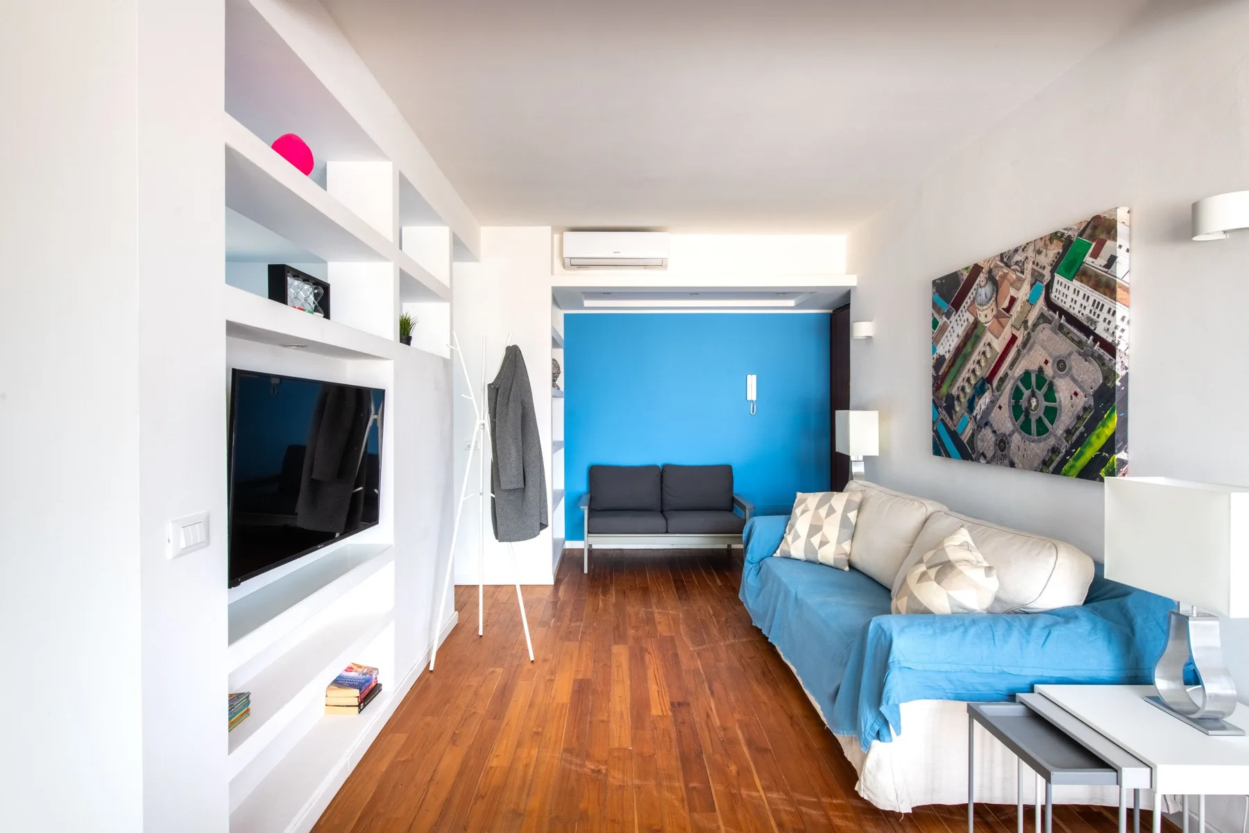 A bright living room with blue seating, a television, and a blue accent wall.