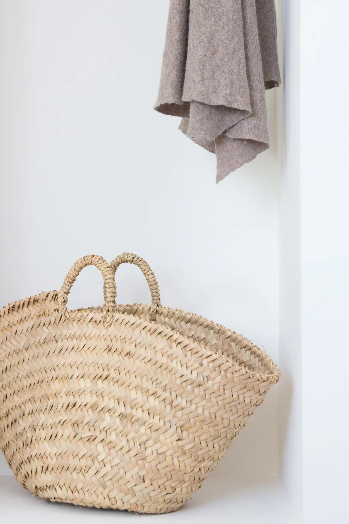 A woven basket rests beneath a hanging towel in a bright interior.