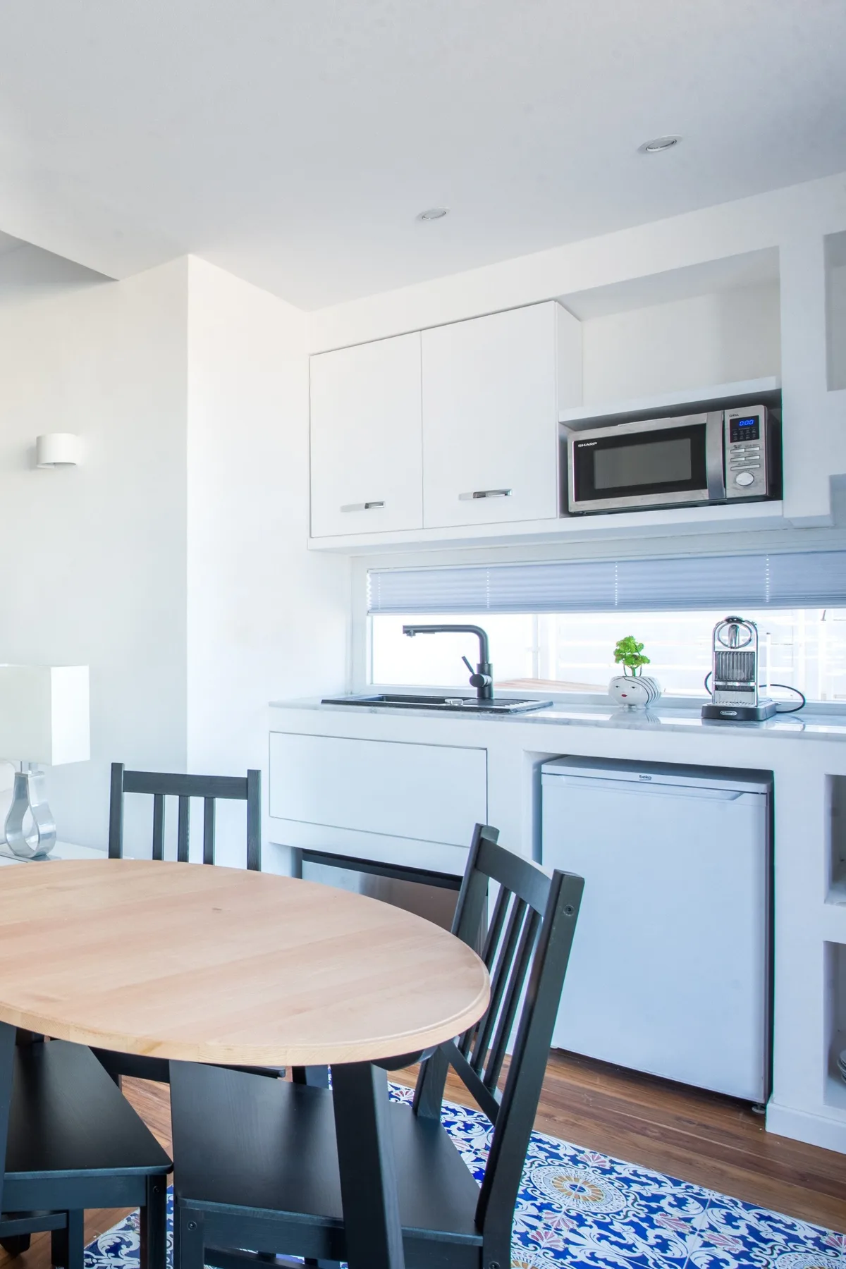 A bright dining area with a round table beside a compact kitchen.
