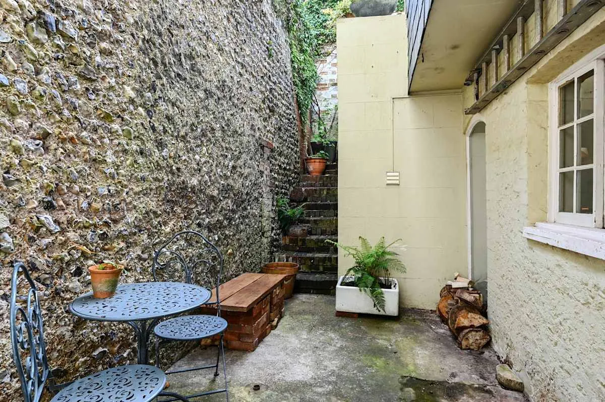 Un pequeño patio con asientos al aire libre, plantas en macetas y escalones.
