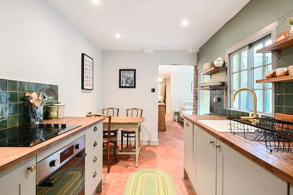 Una cocina luminosa con encimeras de madera, una placa de cocción y una mesa de comedor.