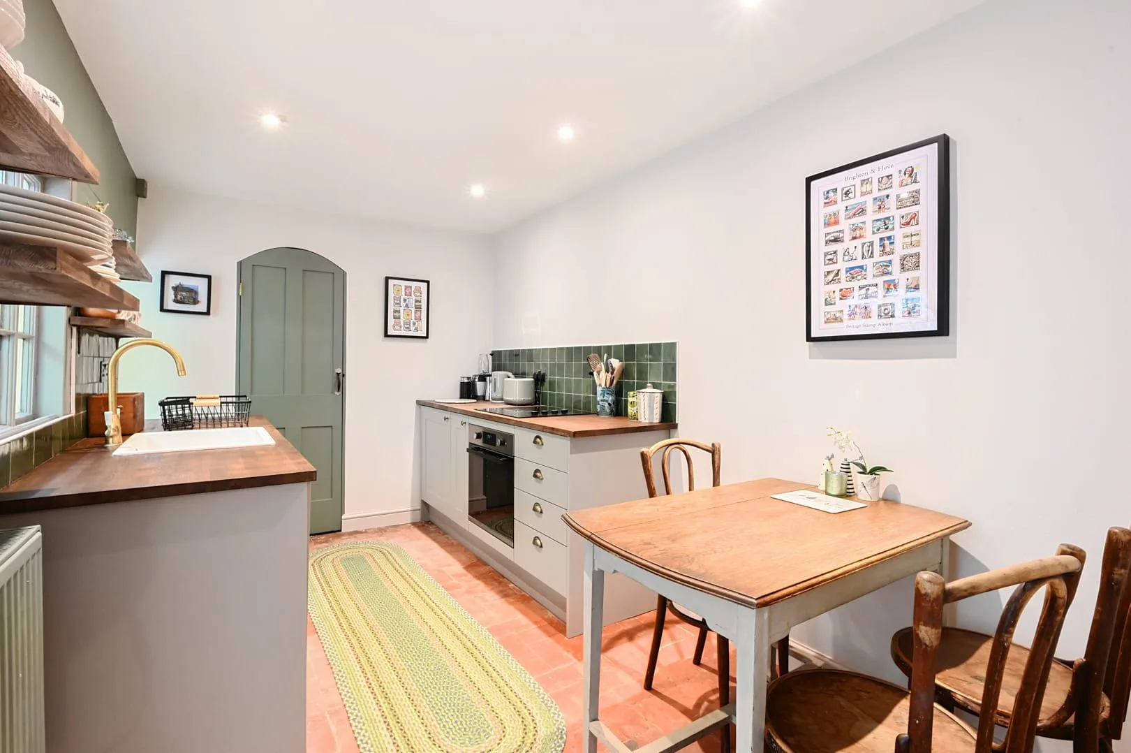 Una cocina luminosa con zona de comedor, mesa de madera y gabinetes verdes.