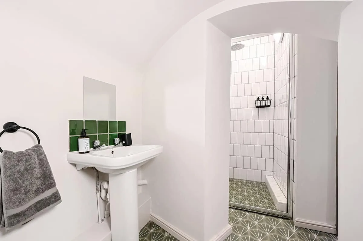 Un baño con lavabo de pared y una ducha alicatada.
