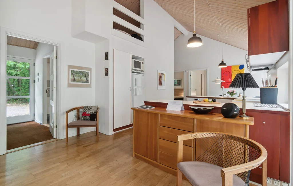 Una cocina y comedor de planta abierta con una isla de madera y lámparas colgantes.