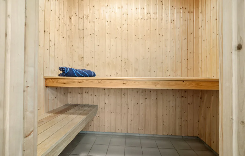 Una sauna revestida de madera con un banco y toallas azules dobladas.