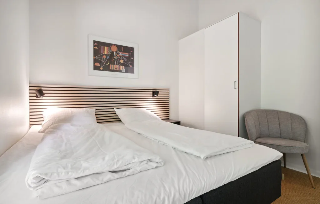 Un dormitorio con una cama, arte en la pared y una silla.