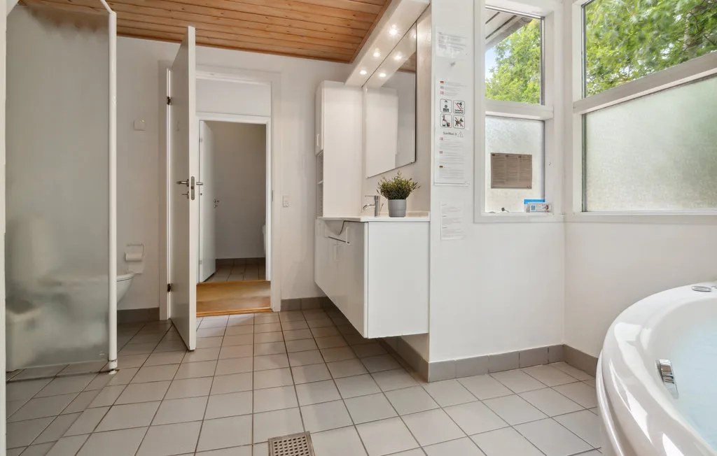 Un baño luminoso con ducha de vidrio, lavabo y ventanas grandes.
