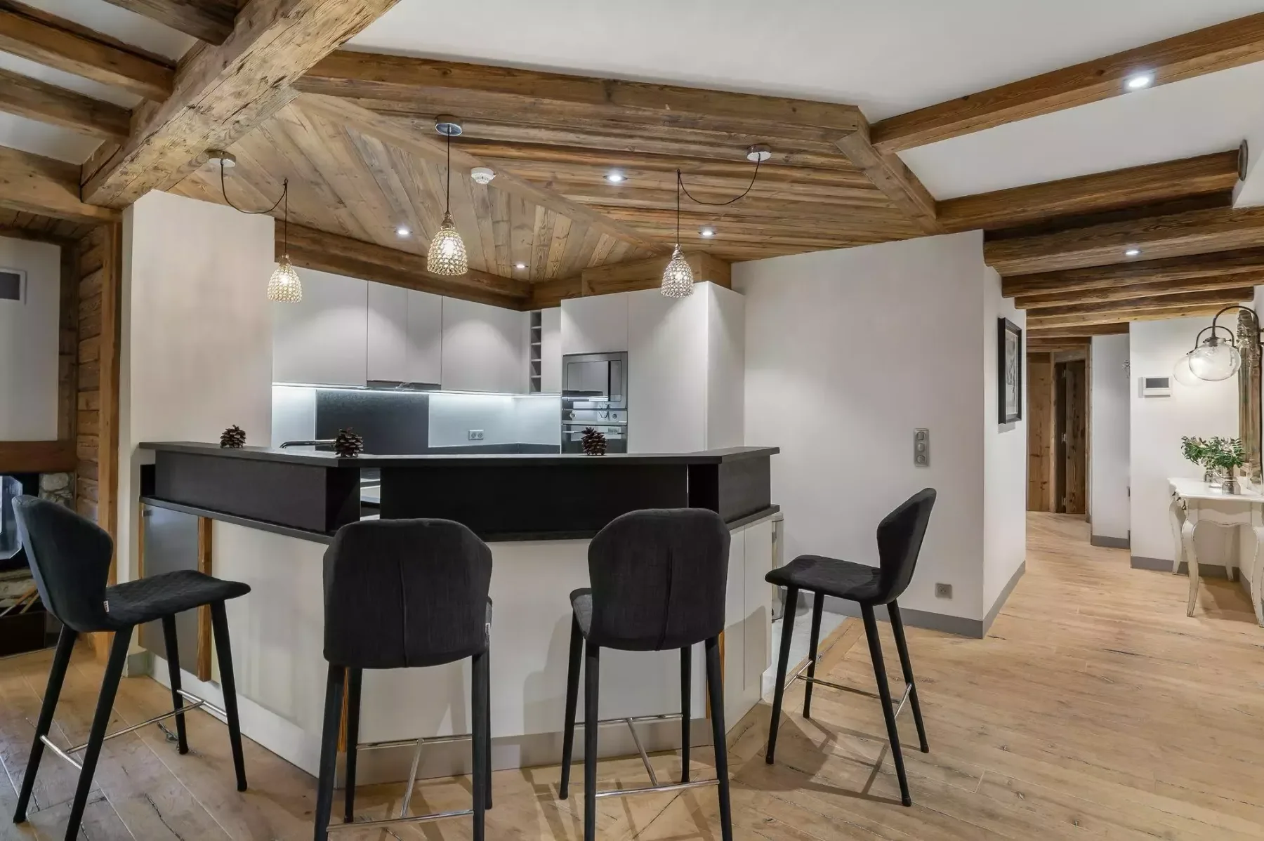 Una cocina con una barra oscura y asientos bajo vigas de madera expuestas.