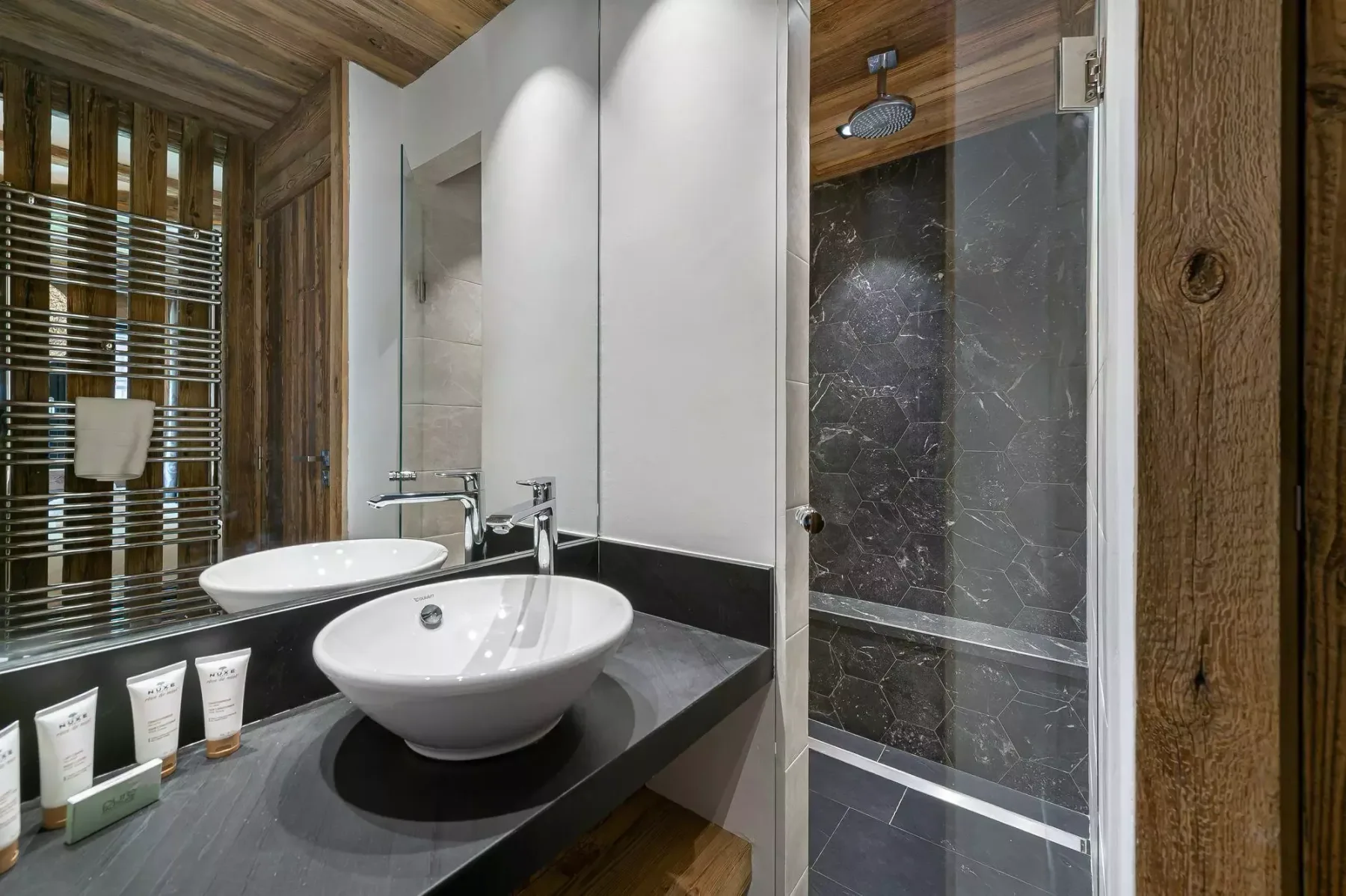 Un baño moderno con lavabo sobre encimera junto a una ducha de vidrio.