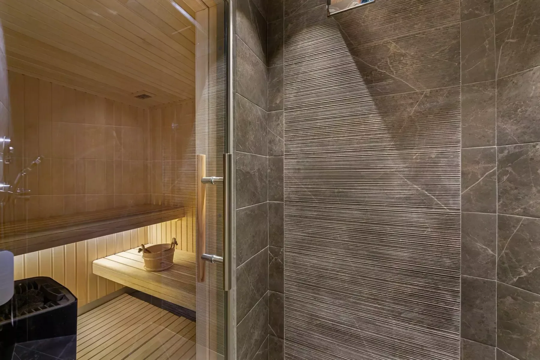 Se ve una sauna de madera junto a una zona de ducha con azulejos.