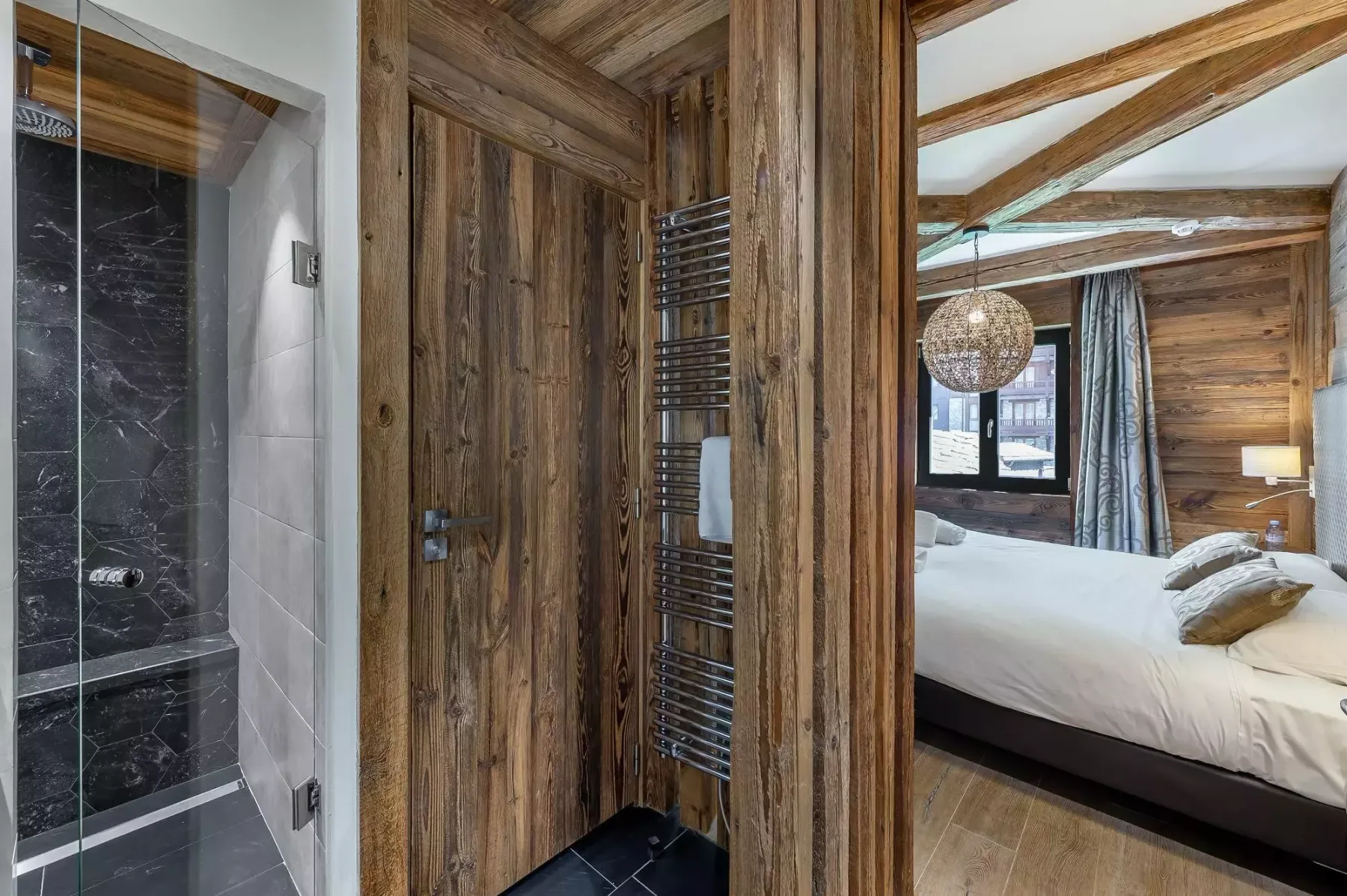 Un dormitorio con una cama junto a una zona de baño revestida de madera.