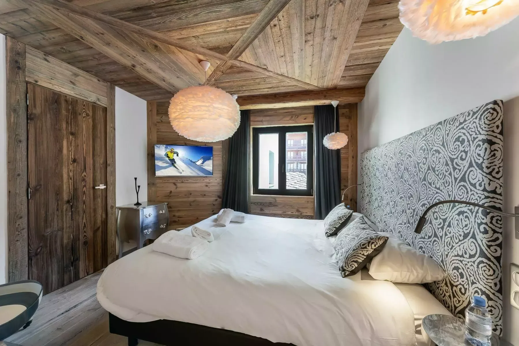 Un dormitorio con una cama grande, un cabecero estampado y paredes revestidas de madera.