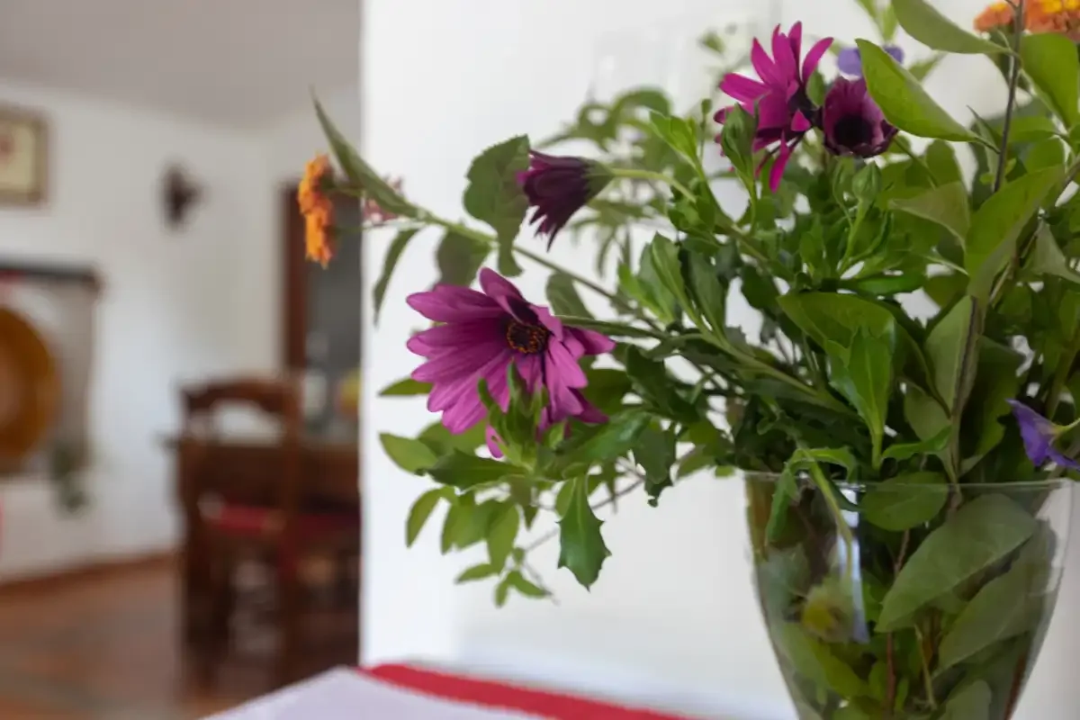 A vase of purple flowers sits on a table in a dining room.