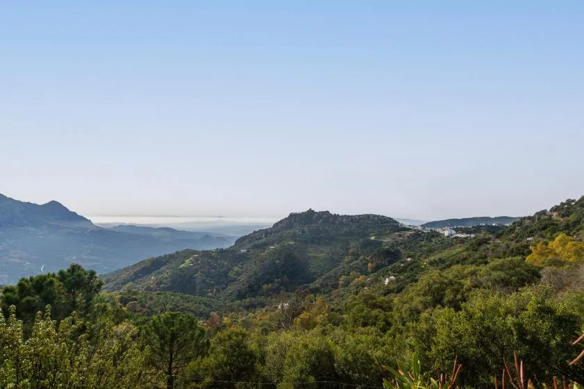 A broad mountain landscape with rolling green hills beneath a clear sky.
