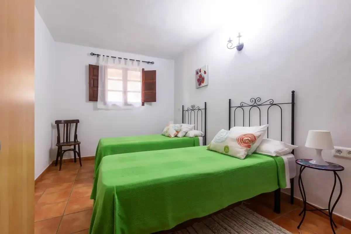 A bedroom with two beds covered in bright green bedspreads.